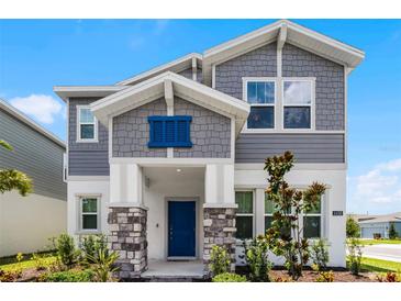Charming two-story home featuring stone accents, a blue front door, and beautifully landscaped front yard at 6458 Pine Warbler Way, St Cloud, FL 34771