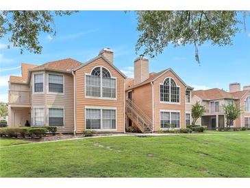 Condo exterior featuring well-manicured lawn, beige siding, and a staircase leading to the upper levels at 698 Roaring Dr # 382, Altamonte Springs, FL 32714