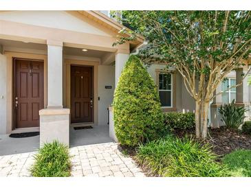 Inviting front entrance with a decorative shrub and a wood-finished front door enhanced by neutral-toned pillars at 11686 Water Run Aly, Windermere, FL 34786