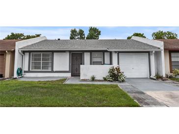 Charming single-story home with a well-maintained lawn, painted in white with gray trim, a single car garage and nice landscaping at 1184 Calanda Ave, Orlando, FL 32807