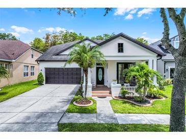 Charming home featuring a manicured lawn, beautiful landscaping, a two-car garage, and a welcoming front porch at 14213 Southern Red Maple Dr, Orlando, FL 32828