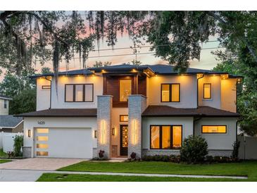Striking two-story home with ambient outdoor lighting, complemented by a brick driveway and a well-manicured front lawn at 1620 S Eola Dr, Orlando, FL 32806