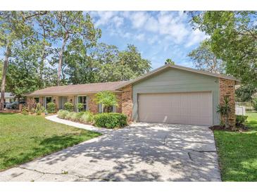 Charming one-story brick home with well-manicured lawn, mature trees, and a two-car garage at 223 Royal Oaks Cir, Longwood, FL 32779