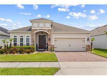 Charming single-story home featuring a brick driveway, neutral stucco, stone accents, and a well-manicured lawn at 337 Meadow Pointe Dr, Haines City, FL 33844
