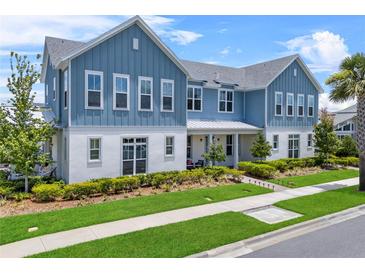 Charming two-story blue and white home featuring a well-manicured lawn and inviting front porch at 8427 Modiano St, Orlando, FL 32827