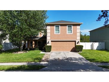 Two-story home featuring a two-car garage, well-manicured lawn, and mature tree at 14308 Abington Heights Dr, Orlando, FL 32828
