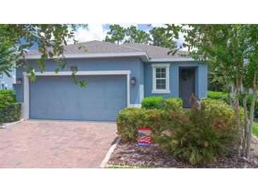 Charming single-story home with a brick driveway, lush landscaping, and a welcoming blue exterior at 1529 Chelsea Manor Cir, Deland, FL 32724