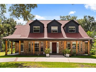 Charming brick home featuring a covered porch with exposed beams and dormer windows at 1815 Big Oak Ln, Kissimmee, FL 34746