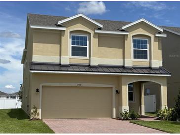 Inviting two-story home featuring a two-car garage, arched entry, tan stucco, and a well-maintained lawn at 1855 Church Lake St, Groveland, FL 34736