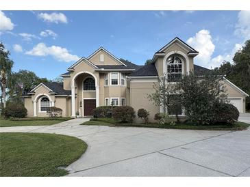 Stately tan home boasting an elegant entrance, arched windows, and lush landscaping at 1865 S Tanner Ct, Deltona, FL 32738