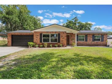 Charming brick home featuring a well-manicured lawn and attached garage at 209 Carriage Hill Dr, Casselberry, FL 32707