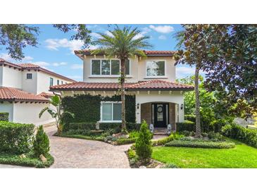 Stunning two-story home with a tile roof, beautiful landscaping, and an inviting brick walkway leading to the front door at 800 Hamilton Place Ct, Winter Park, FL 32789