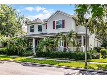 Charming two-story home with lush landscaping, red shutters, and a welcoming front porch with columns at 8113 Key West Dove St, Winter Garden, FL 34787