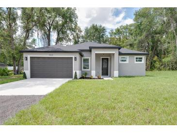 Charming one-story home featuring a gray exterior, dark roof, well-manicured lawn and two car garage at 1868 14Th St, Orange City, FL 32763