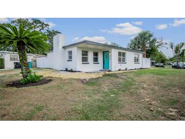 Charming single-story home with a well-maintained lawn, white fence and a blue front door at 4420 Lake Lawne Ave, Orlando, FL 32808