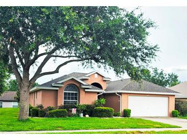 Charming single-story home with mature trees, well-manicured lawn, and a two-car garage at 4471 Treasure Cay Rd, Tavares, FL 32778