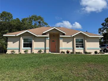 Charming single-story home with a well-maintained lawn, neat flowerbeds, and an inviting coral colored front door at 56 Redwood Rd, Ocala, FL 34472