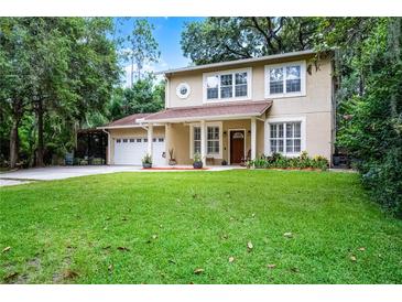 Charming two-story home with a well-manicured lawn, attached garage, and front porch perfect for relaxing outdoors at 14202 Nell Dr, Orlando, FL 32832