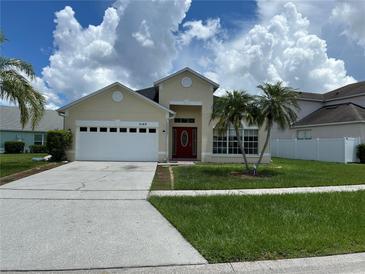 Charming home with a well-maintained lawn, palm trees, a two-car garage, and a vibrant red front door at 2149 Mallard Creek Cir, Kissimmee, FL 34743