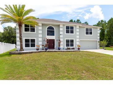Charming two-story home with a palm tree, green lawn, and well manicured landscaping at 4064 Sunny Day Way, Kissimmee, FL 34744
