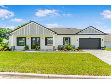 Charming single-story home with a well-manicured lawn, dark shutters, and an attached two-car garage at 1006 Linkside Ct, Apopka, FL 32712