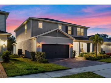 Charming two-story home with a well-manicured lawn and a two-car garage under a colorful dusk sky at 4316 Foggy Oak Ln, Sanford, FL 32773