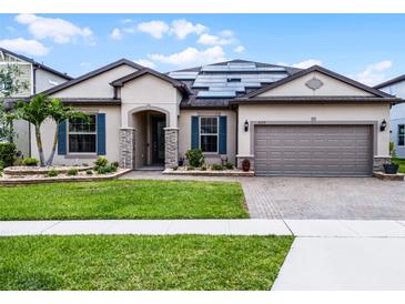 Charming single-story home with a manicured lawn, brick driveway, beautiful landscaping and solar panels at 5029 Hartwell Ct, St Cloud, FL 34771