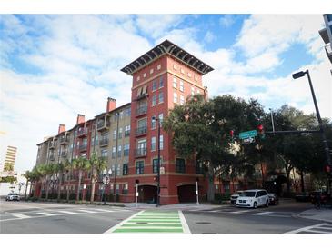 Attractive condo building exterior with balconies, colorful facade, palm trees and street view on a sunny day at 911 N Orange Ave # 143, Orlando, FL 32801