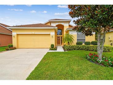 Inviting yellow home with a well-manicured lawn and a two-car garage at 1041 Cherry Valley Way, Orlando, FL 32828