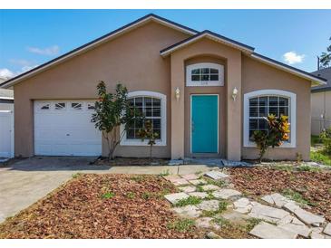 Charming single-story home with a well-maintained lawn, a teal front door and an attached garage at 1115 Naples Dr, Orlando, FL 32804