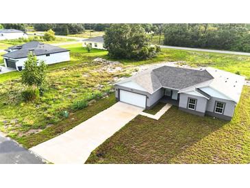 Charming gray home boasts a long driveway, attached garage, and a freshly seeded lawn at 1304 Hillsborough Ct, Kissimmee, FL 34759