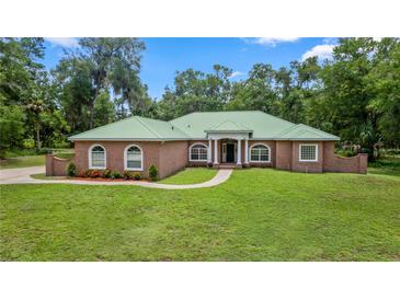 Charming one-story brick home with a green roof, arched windows, and a well-manicured lawn at 1908 S Farm Rd, Deland, FL 32720