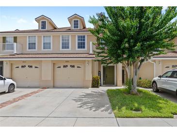 Inviting townhome featuring a well-maintained lawn, two-car garage, and charming architectural details at 3055 Ashland N Ln, Kissimmee, FL 34741