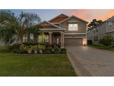 Charming two-story home featuring a well-manicured lawn, lush landscaping, and a welcoming front porch at 3404 Shallow Cove Ln, Clermont, FL 34711