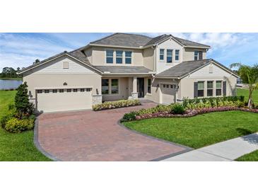 Beautiful two-story home with a brick driveway, two-car garage, manicured landscaping, and beige stucco exterior at 10117 Atwater Bay Dr, Winter Garden, FL 34787