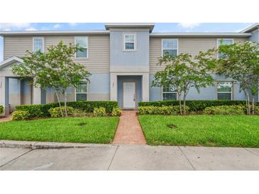 Charming two-story townhome with a well-maintained lawn, decorative shrubbery, and a brick path leading to the front door at 141 Claire Ln, Davenport, FL 33837