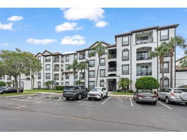 Beautiful multi-story condo building with white facade, dark trim, balconies, and lush tropical landscaping at 4114 Breakview Dr # 110, Orlando, FL 32819