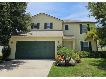 Two-story home with a well-manicured lawn, two-car garage, and dark green shutters at 4901 Stone Acres Cir, St Cloud, FL 34771