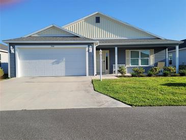 Charming single-story home featuring a two-car garage, well-manicured lawn, and cozy front porch at 744 Barron Pl, The Villages, FL 32163