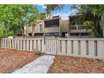Townhouse exterior with wood fence, leafy trees, and walkway leading to front doors at 108 Crown Oaks Way, Longwood, FL 32779