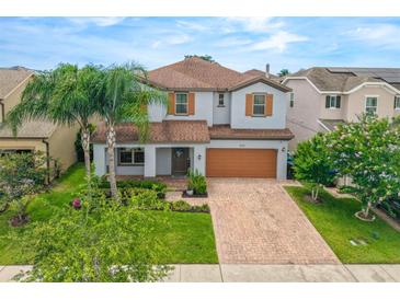 Charming two-story home with manicured lawn, a brick driveway, and tan trim at 1270 Fountain Coin Loop, Orlando, FL 32828