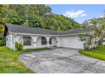 Charming single-story home featuring an arched portico and a spacious driveway leading to an attached garage at 1533 Ravana Dr, Orlando, FL 32822