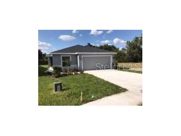 Charming single-Gathering home features a gray exterior, well-manicured lawn, and a paved driveway leading to an attached garage at 4844 Summerfield Cir, Winter Haven, FL 33881