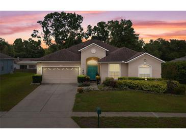 Charming single-story home with a well-manicured lawn, colorful flower beds, and a two-car garage at sunset at 813 Lancer Cir, Ocoee, FL 34761