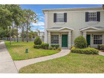 Inviting townhome featuring a well-manicured lawn and charming curb appeal with a green door at 9492 Flowering Cottonwood Rd # 82, Orlando, FL 32832