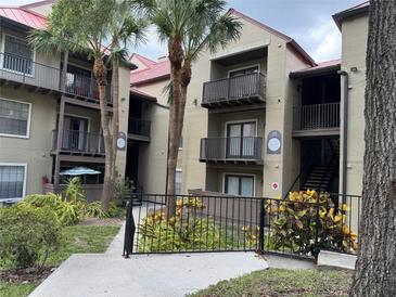 Condo building with palm trees, balconies, a red roof, and black metal fencing in a lush green landscape at 199 Afton Sq # 108, Altamonte Springs, FL 32714