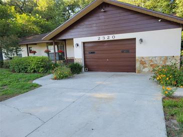 Charming home featuring a well-maintained front yard with a stone facade and attached garage at 2320 Ne 43Rd St, Ocala, FL 34479