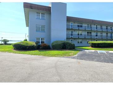 A view of the condo building's exterior shows landscaping, covered walkways, and easy access parking at 333 Lake Howard Nw Dr # 201A, Winter Haven, FL 33880