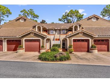 Charming condo building with arched entryways, red garage doors, and lush landscaping at 7421 Sugar Bend Dr # 7421, Orlando, FL 32819