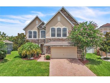 Stunning two-story home featuring stone accents, a brick driveway, and lush landscaping at 14342 Fieldstone Lake Way, Orlando, FL 32824